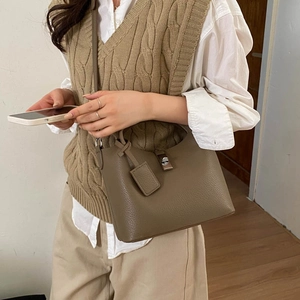 Close-up of deep brown lychee texture leather bucket bag with metal lock and tag