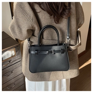 Sac bandoulière noir classique avec boucle en métal et doubles poignées porté par un modèle