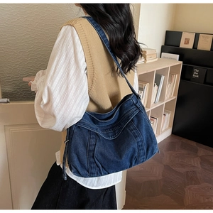 Détail d'un grand sac cabas en denim bleu foncé avec logo embossé et large bandoulière