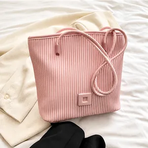 Détail d'un sac cabas plissé rose avec ornement carré sur un fond en tissu doux