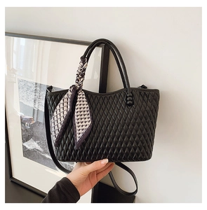 Detalle de bolso tote acolchado negro con un pañuelo de seda decorativo en el asa