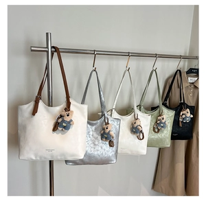Row of leather tote bags in five colors with cute teddy bear charms on a display rack