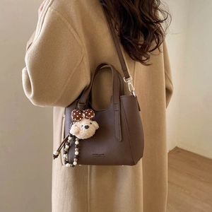 Brown bucket bag styled with a beige coat and cute plush puppy charm detail