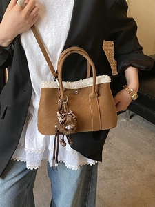 Brown suede bucket bag with white faux fur trim and cute monster charm shown on model