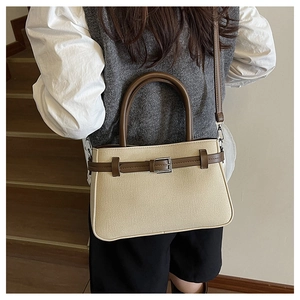 Détail du sac à main minimaliste en toile beige avec lanières en cuir marron et boucle