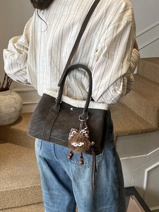 Brown suede tote bag with faux fur trim, leopard bow and cute charm on studio background