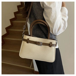Détail d'un sac à bandoulière en toile crème avec garniture en cuir marron sur un modèle