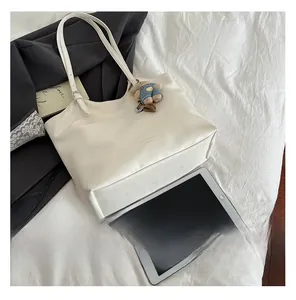 Top view of white large tote bag with teddy bear pendant and office accessories