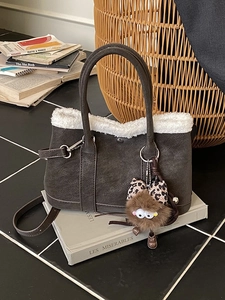 Brown suede bucket bag with white faux fur trim and cute plush charm on retro books