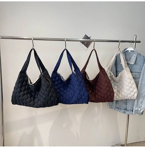 Detailed heart-quilted texture on oversized puffer tote bags in four essential colors