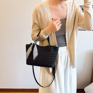 Detalle de bolso acolchado negro con un pañuelo decorativo de seda con diseño geométrico