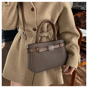 Détail du sac à main en cuir marron foncé avec boucle argentée et profil latéral élégant