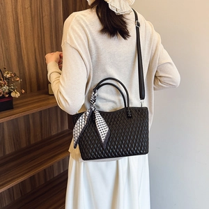 Detalle de bolso tote acolchado negro con un pañuelo de seda decorativo y correa de hombro