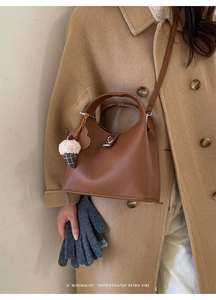 Brown lindy style leather bag with silver buckle and cute plush charm on camel wool coat