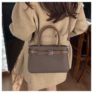Détail du sac à main marron foncé avec boucle argentée porté sur un manteau en laine
