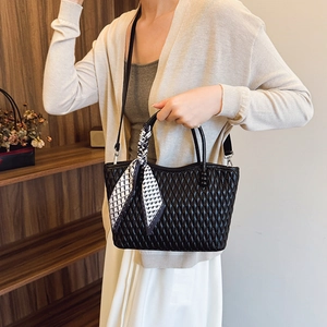 Primer plano de bolso acolchado negro con pañuelo de seda a cuadros en el asa