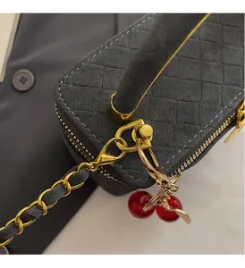 Detailed view of dark grey woven crossbody bag with gold hardware and cherry charm