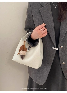 Detail of white lychee leather bucket bag featuring silver lock and lovely heart charm