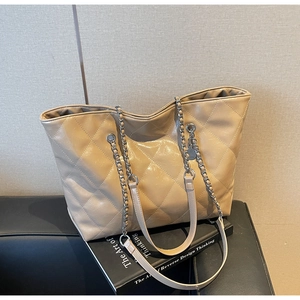Detail of light beige quilted leather tote bag with metal chain shoulder strap and pattern