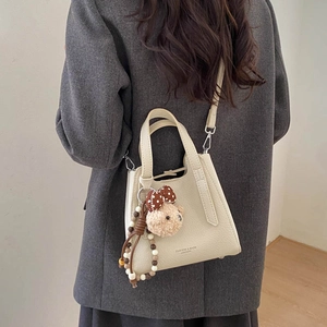 Creamy white bucket bag with pebble leather texture and cute plush bear keychain charm
