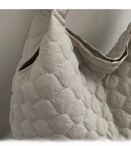 Close-up of quilted tote bag showing white contrast stitching and soft nylon texture