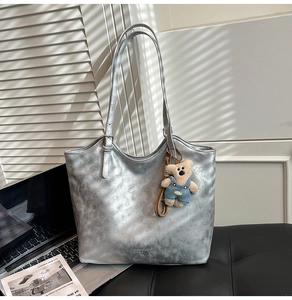 Macro view of silver tote bag featuring crackle leather texture and cute bear charm