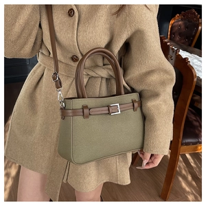 Détail du sac tissé vert foncé avec poignées en cuir marron et boucle en métal argenté