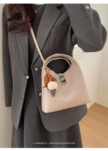 Detail of lychee pattern leather bucket bag with metal clasp and decorative charms