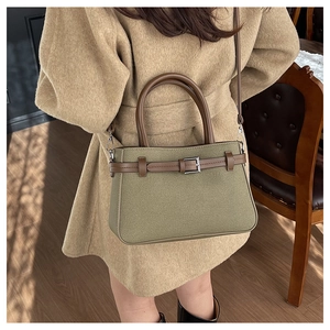 Détail du sac à bandoulière vert olive texturé avec poignées en cuir et boucle métal