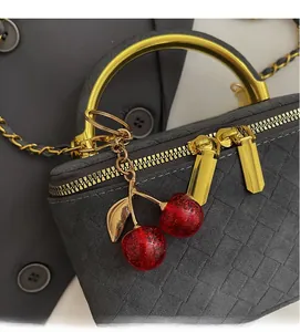 Close-up of grey woven texture handbag with golden handle and sequin cherry charm