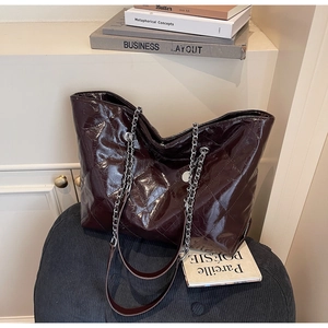 Detail of burgundy quilted patent leather tote bag with silver chain strap and metal eyelet
