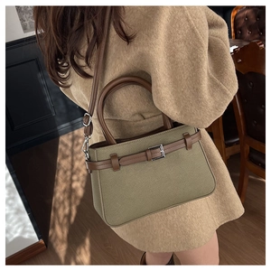 Détail du sac bandoulière en toile verte avec lanières en cuir brun et boucle argentée