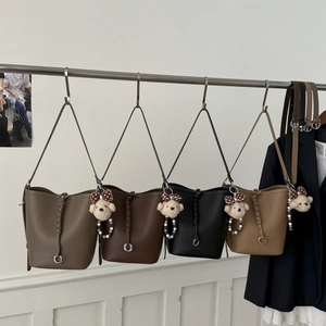 Detail view of four bucket bags in brown, khaki, and black with cute bear charms