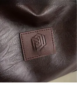 Gros plan du logo embossé sur le sac de sport en cuir grainé marron de haute qualité