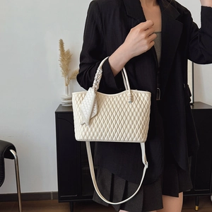 Detalle de bolso acolchado crema con asa trenzada llevado por una modelo en negro