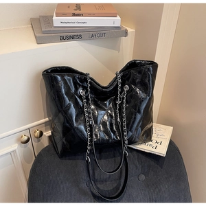 Detailed view of black quilted faux leather tote bag with silver chain straps and large interior