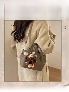 Detail of khaki pebbled leather bucket bag with cute teddy bear charm and strap