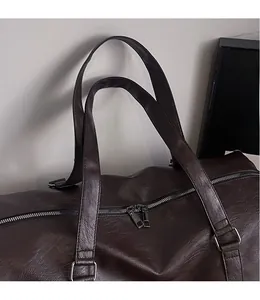 Détail du sac de voyage en similicuir marron foncé avec texture et boucles argentées