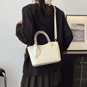 Detalle de bolso acolchado crema con asa de pañuelo de seda y correa de hombro ajustable