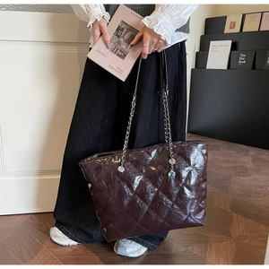 Detail of dark brown quilted leather tote bag with metallic chain and glossy finish