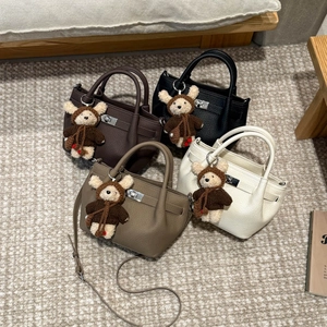 Detail of four textured leather bucket bags with metal turn-lock and cute bear charms