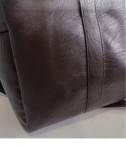 Gros plan d'un sac de sport marron foncé en similicuir grainé avec surpiqûres précises
