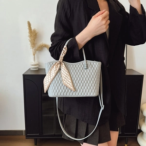 Detalle de bolso acolchado azul claro con pañuelo de seda en el asa redonda