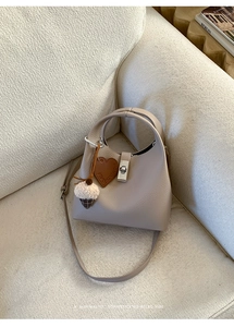 Detailed macro view of beige lychee leather bucket bag with heart and nut charms