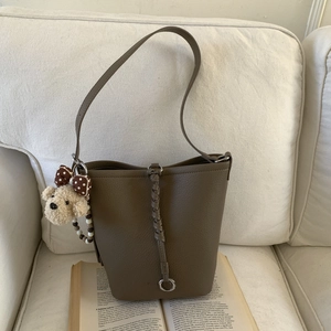 Detail of brown litchi pattern leather bucket bag with woven straps and cute puppy charm