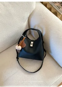 Detail of black lychee leather bucket bag with silver lock and ice cream charm on sofa