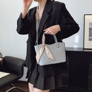 Bolso bandolera acolchado con pañuelo decorativo en el asa mostrado por una modelo