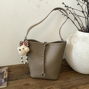 Detail showing pebbled clay brown leather texture and woven strap with bear charm