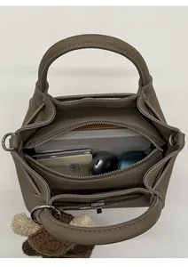 Top view of spacious bucket bag interior with gadgets and a crochet bear charm