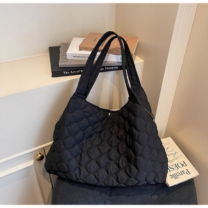 Macro shot of black quilted tote bag texture and soft padded shoulder strap detail